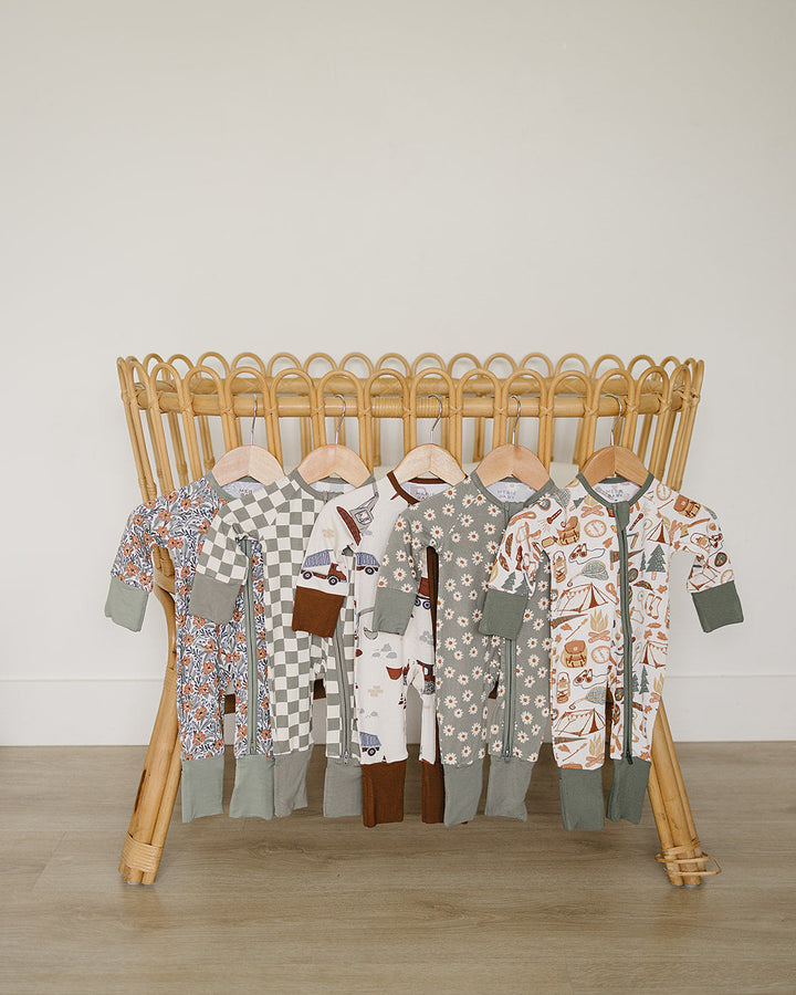 Collection of baby rompers on a wooden rack against a plain wall.