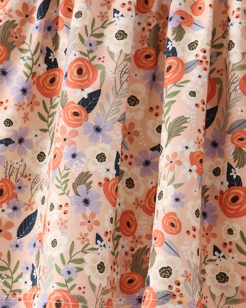 Close-up of a floral fabric with a cream background and a pattern of orange, purple, and green flowers and leaves.
