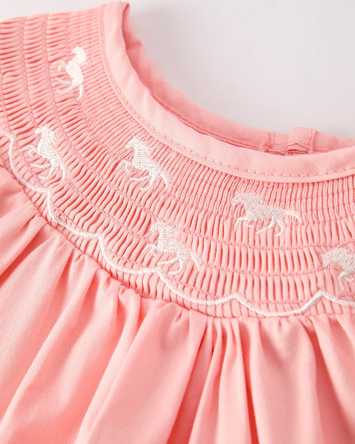 Pink dress with embroidered details on a white background