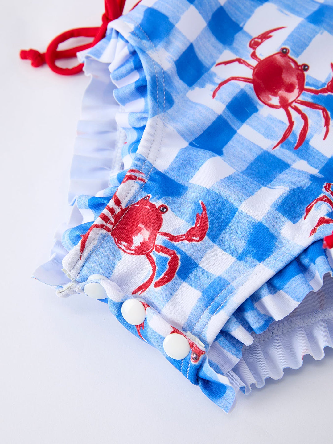 Blue checkered swimsuit with red crabs and white polka dots on a white background