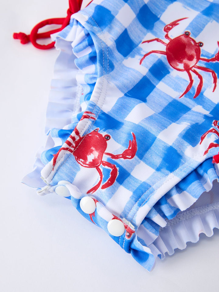 Blue checkered swimsuit with red crabs and white polka dots on a white background