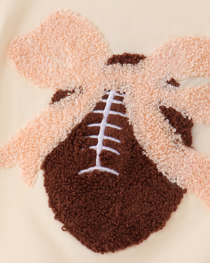 Cream romper front with football applique and stitched laces detail
