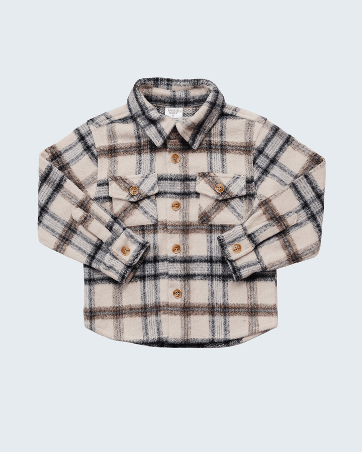A long-sleeve plaid button-up shirt for kids, featuring a cream base with brown and black check lines, brown buttons, and two chest flap pockets, displayed on a light gray background.