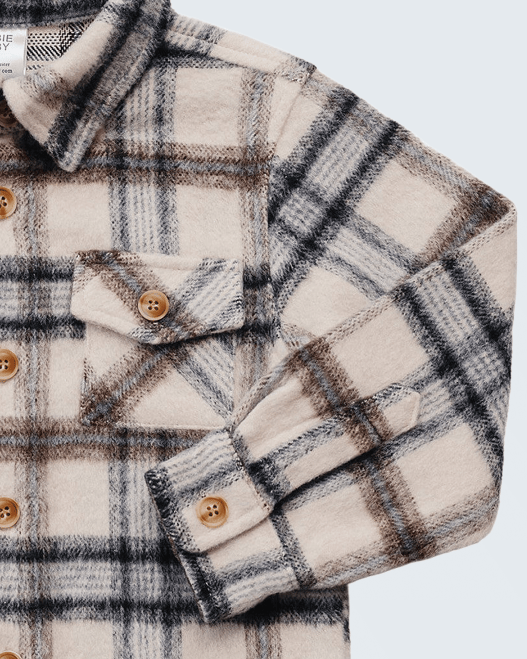 Close-up of a long-sleeve plaid flannel shirt jacket in cream, brown, and black, featuring brown buttons and a chest pocket.