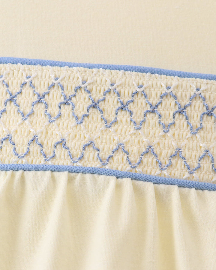 Blue smocked decorative panel across cream romper bodice with gathered elastic trim