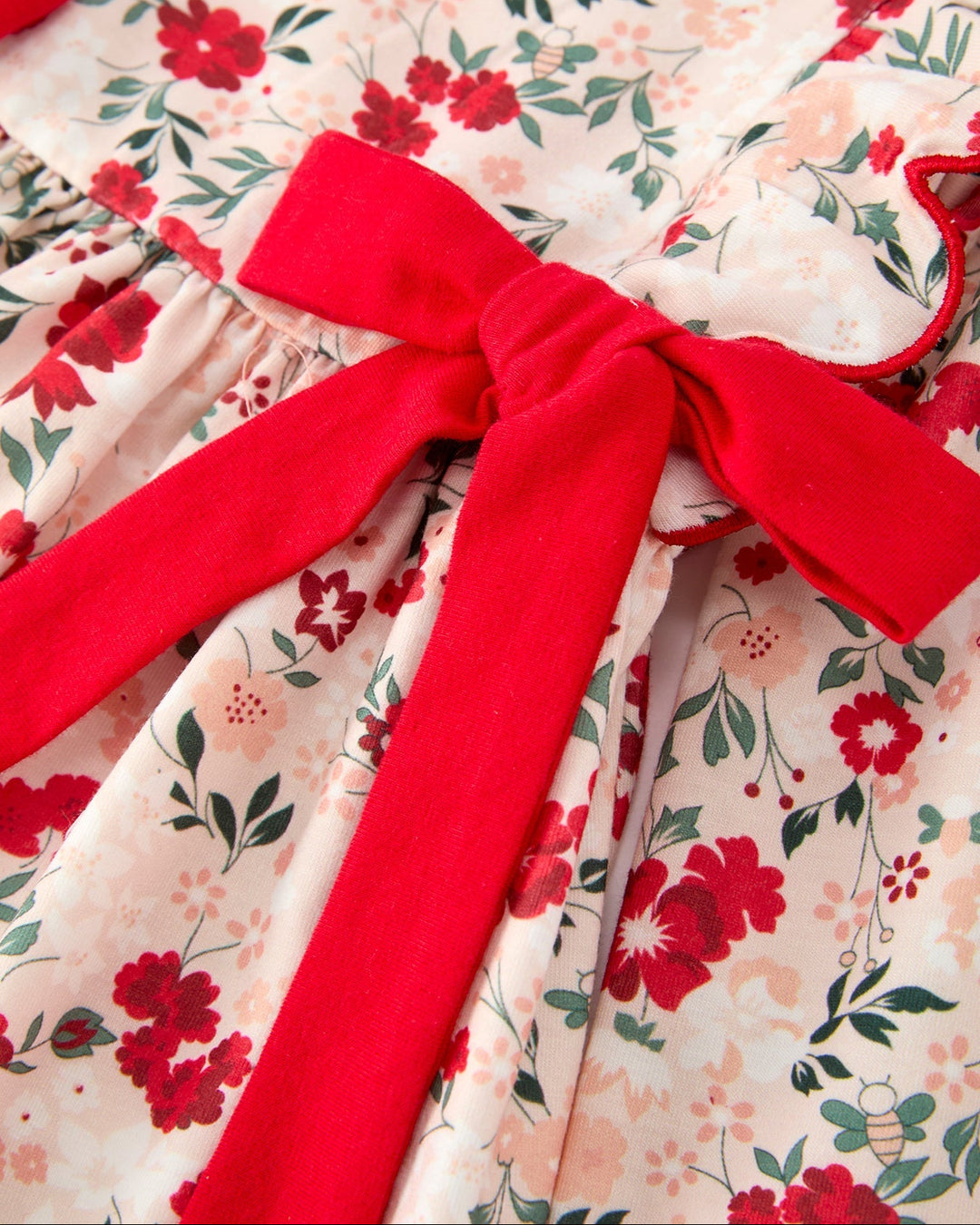 Girls twirl dress close-up: large red bow at waist over floral print