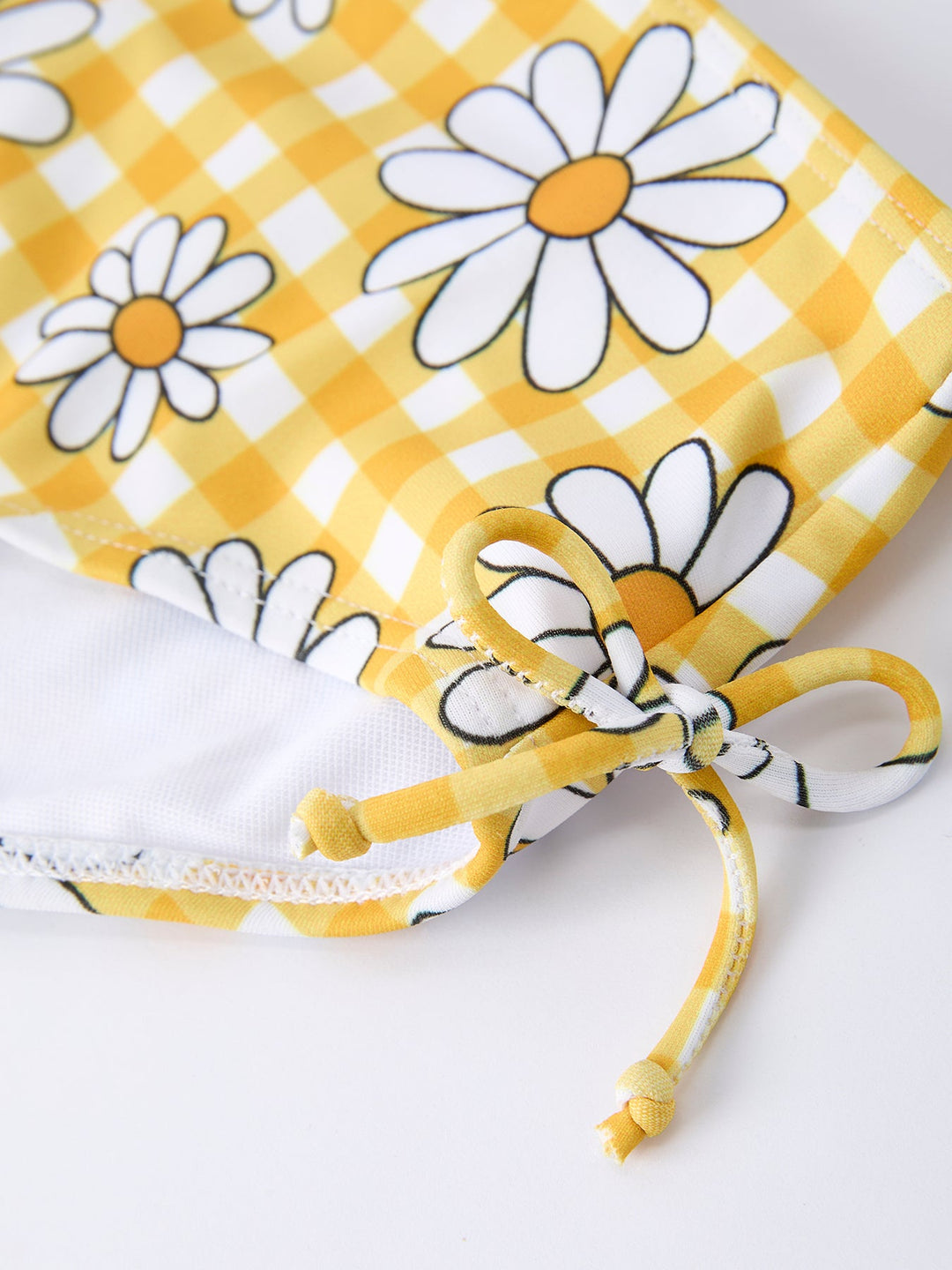 Fabric with yellow checkered pattern and white daisies on a white background
