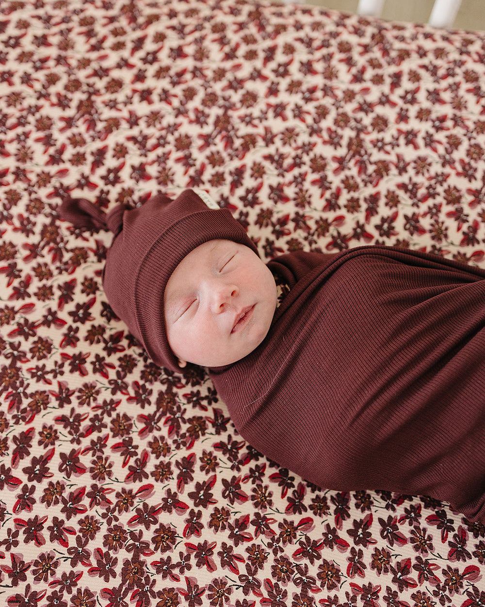 Newborn knot hat in deep violet ribbed knit, worn with folded cuff