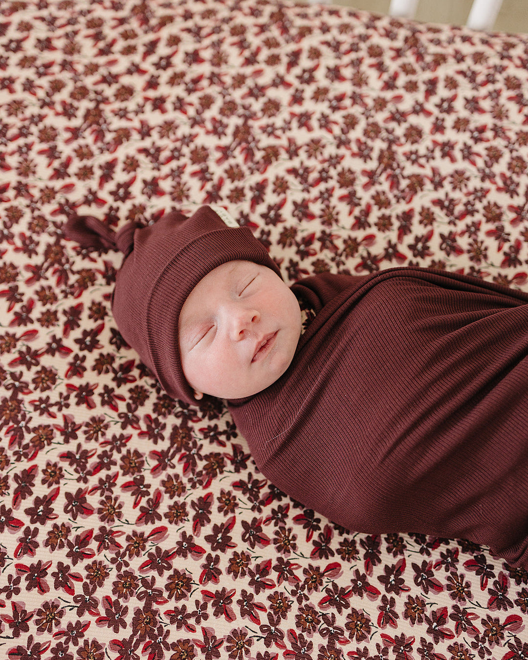 Newborn knot hat in deep violet ribbed knit, worn with folded cuff