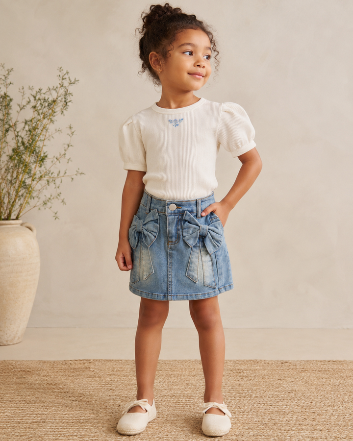 Young girl wearing a denim skirt with bow details