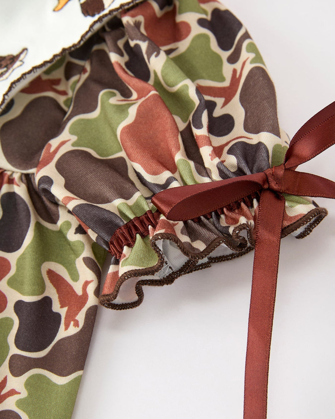 Camouflage-patterned dress with a red ribbon on a white background