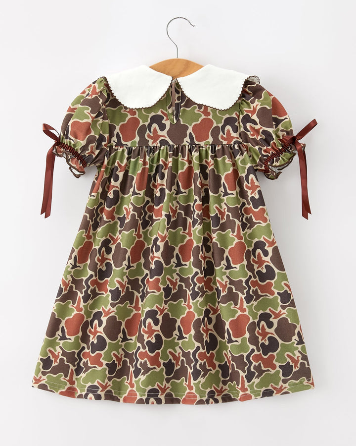 Camouflage-patterned dress with a white collar on a hanger against a white background