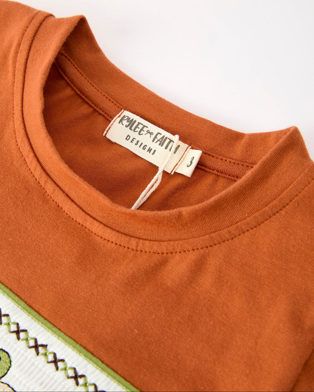 Close-up of an orange shirt with a brand label on a white background
