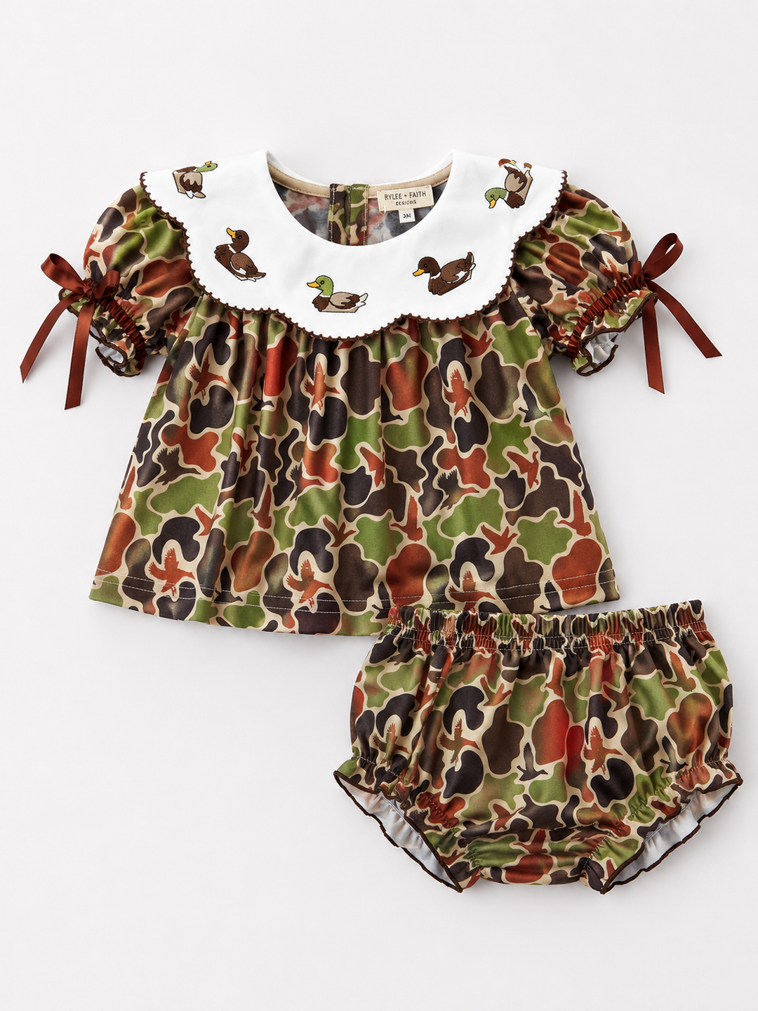 Camouflage-patterned baby outfit with ruffled collar on a white background