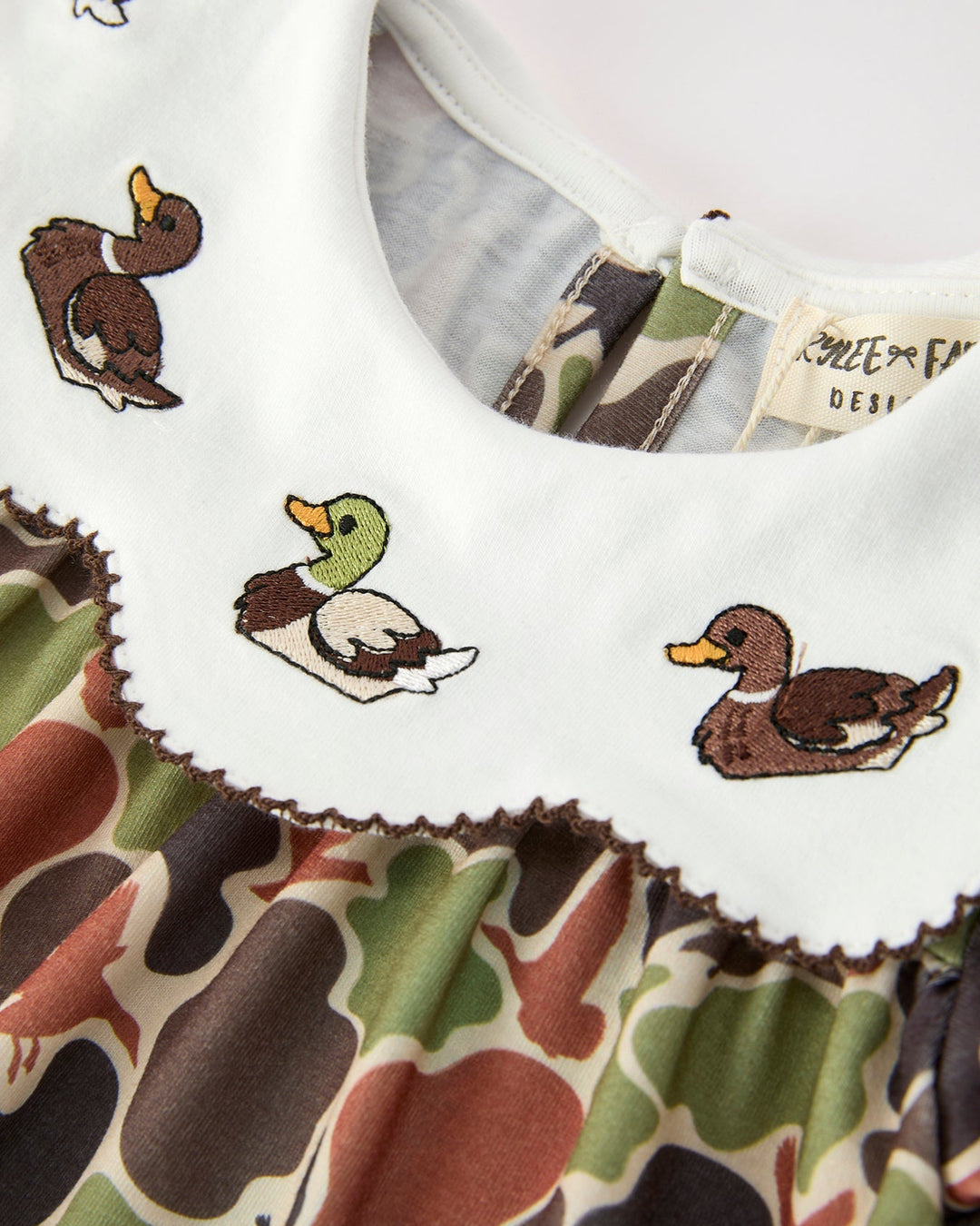 Baby outfit with duck designs on a camouflage background
