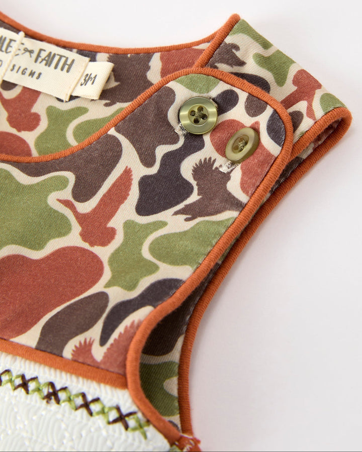 Camouflage-patterned romper with brand label on a white background