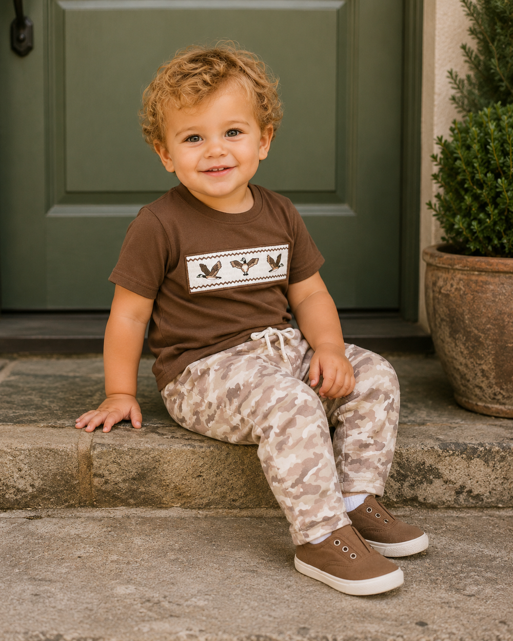 Toddler boy sitting on a step wearing camo outfit