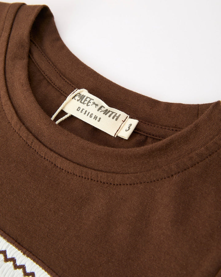 Close-up of a brown garment with a visible label on a white background