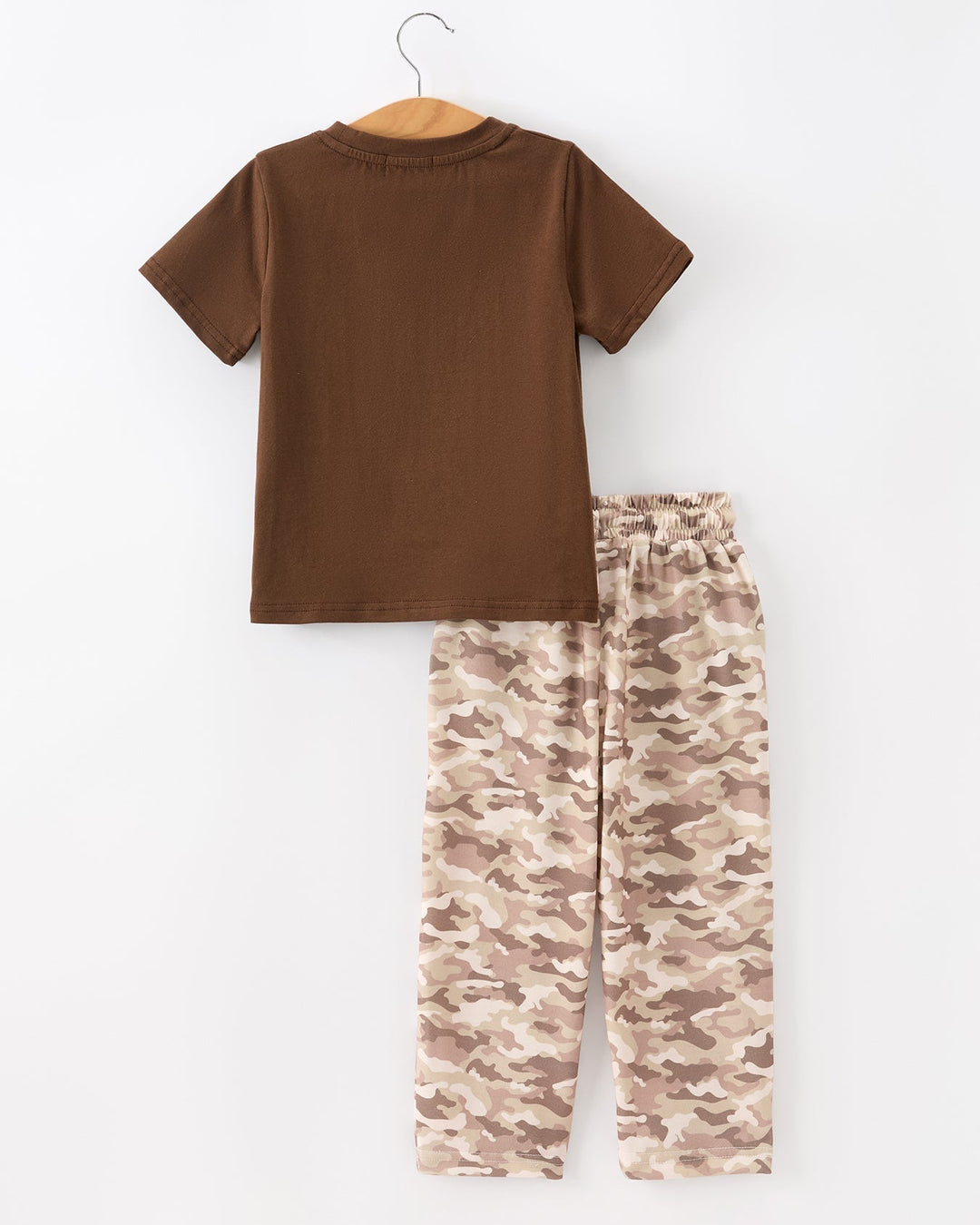Brown t-shirt and camouflage pants on a hanger against a white background