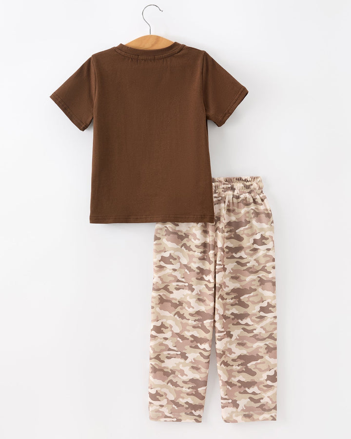Brown t-shirt and camouflage pants on a hanger against a white background