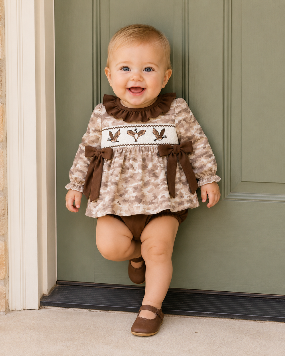 Baby girl leaning up against green door