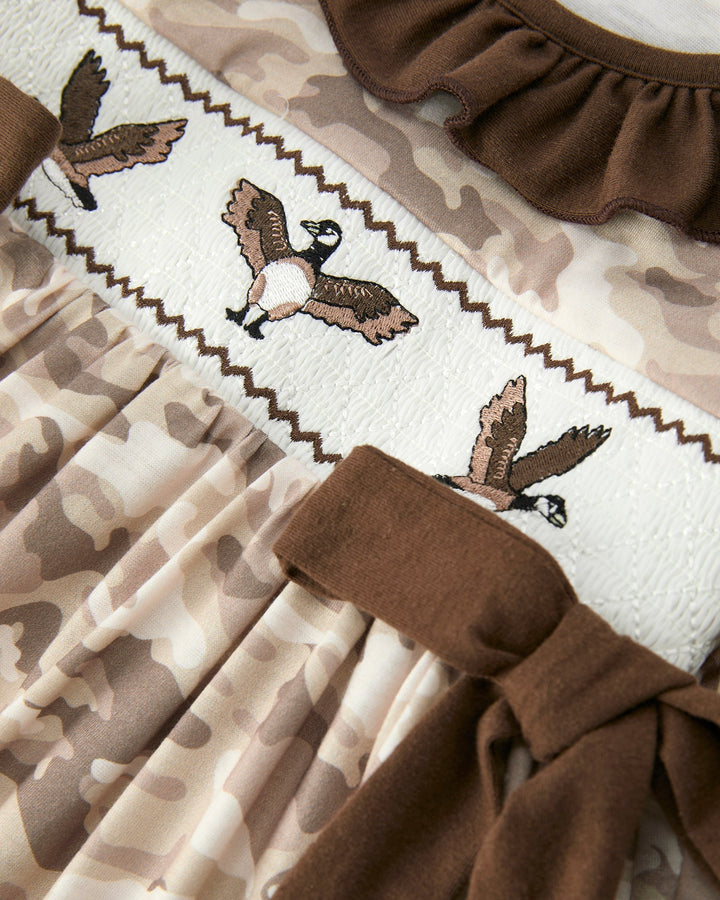 Close-up of a fabric with duck designs and brown ruffled trim on a white background.