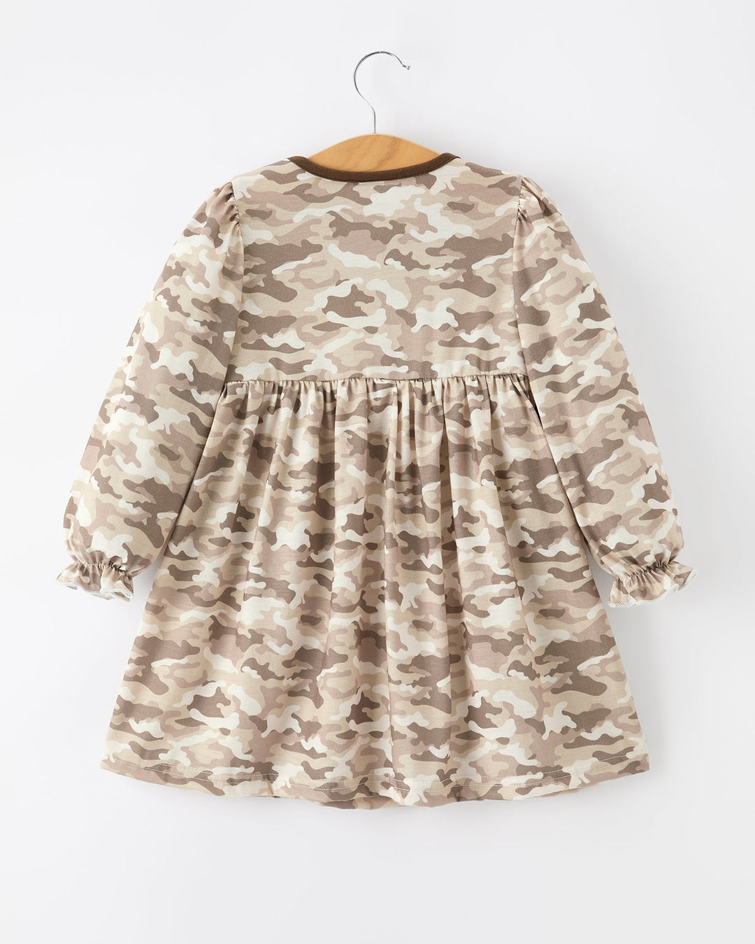 Camouflage-patterned dress on a hanger against a white background