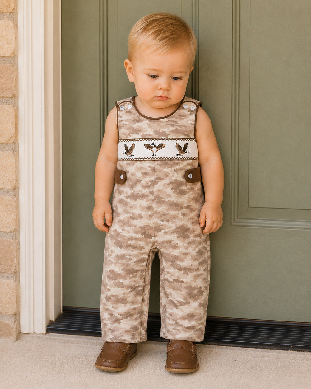 Baby boy standing up against a green door.