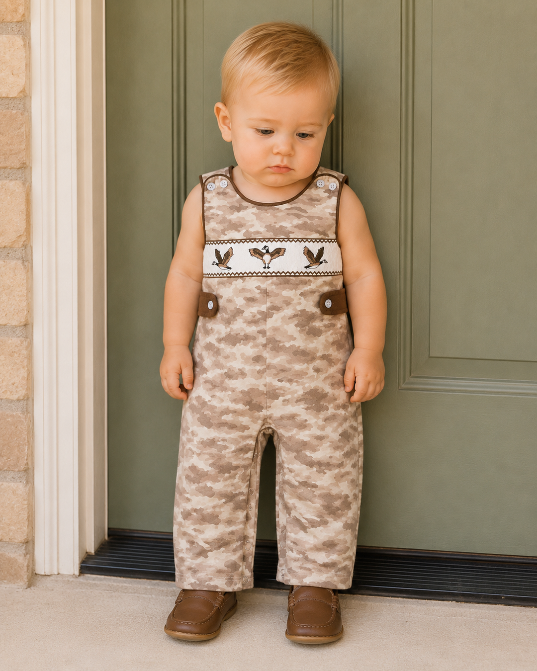 Baby boy standing up against a green door.