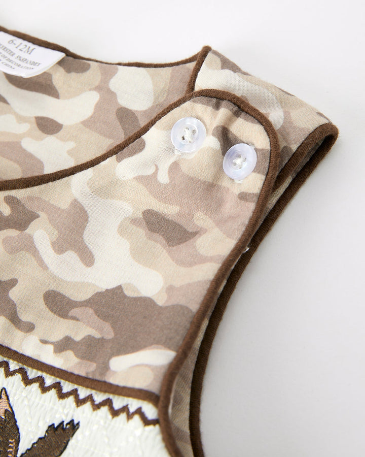 Camouflage-patterned romper with white buttons on a white background