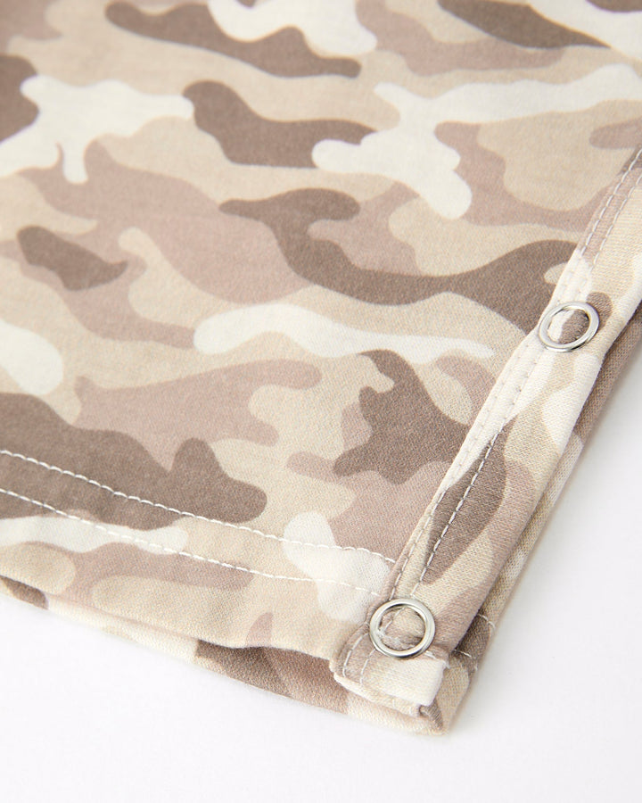 Camouflage-patterned fabric with metal grommets on a white background