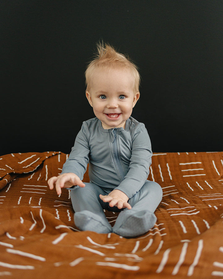Child sitting on a patterned blanket against a black background