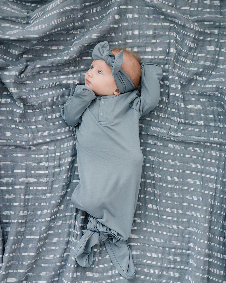 Dusty blue head wrap tied at top with large knot, worn on baby