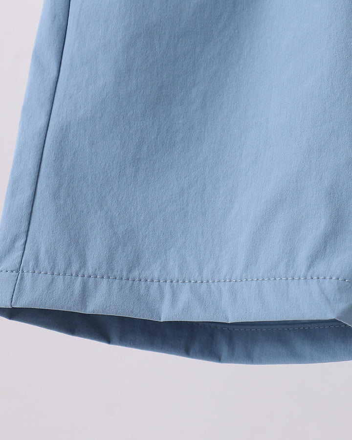 Dusty blue shorts with curved hem and visible stitching along the bottom edge