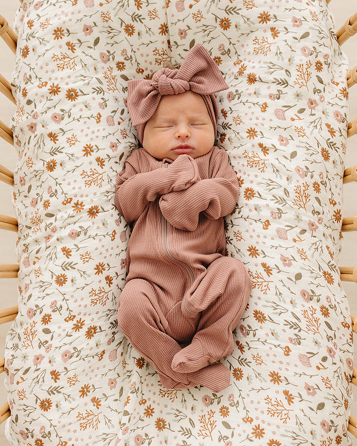 Dusty rose ribbed zipper romper on a baby lounging with long sleeves