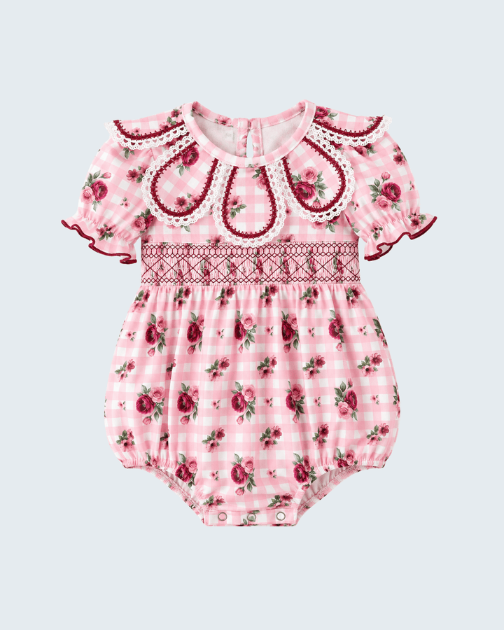 Pink floral romper with embroidered yoke, scalloped neckline, ruffle sleeves, and snaps