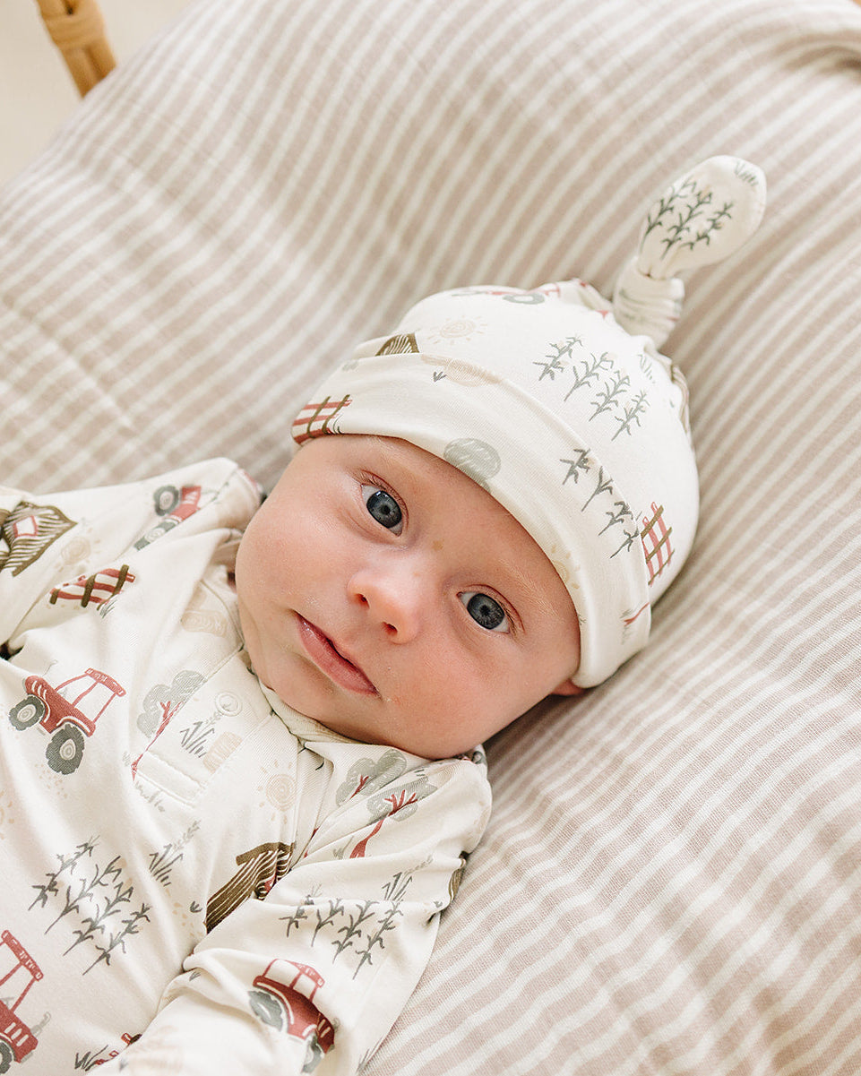 Newborn knot hat on baby with off-white farmhouse pattern and tied crown