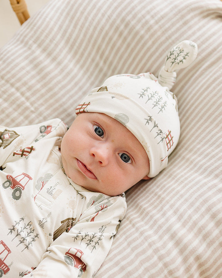 Newborn knot hat on baby with off-white farmhouse pattern and tied crown