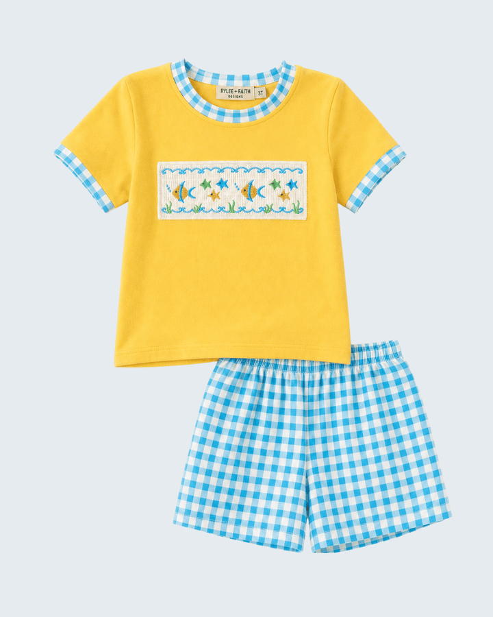 Yellow shirt with fish design and blue checkered shorts on a white background