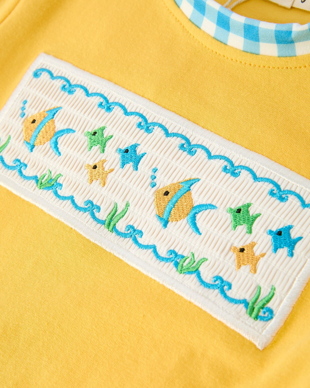 Embroidered border with cartoon fish design on a yellow background