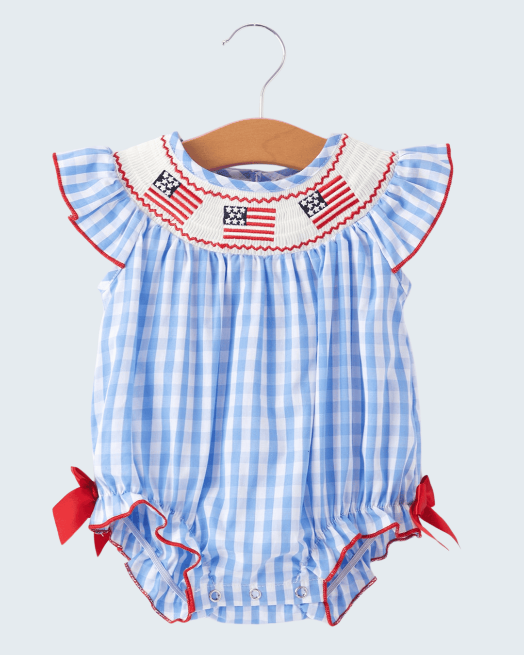 Baby romper with American flag design on a hanger against a light gray background
