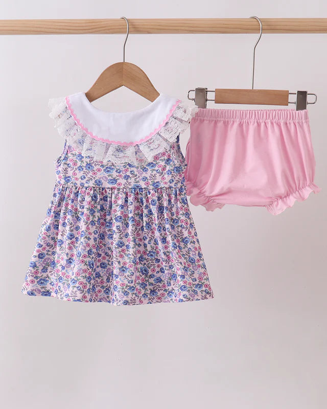 Floral dress and pink bloomers on hangers against a white background