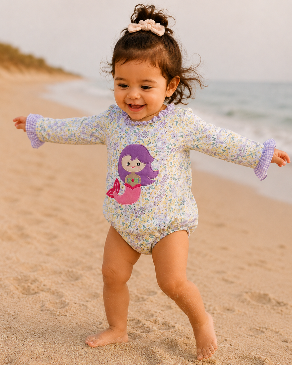 Child in a floral swimsuit with a mermaid design on a beach