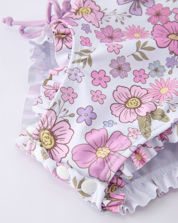 Floral-patterned baby romper with ruffles on a light background