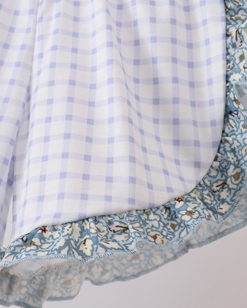 Close-up of a fabric with blue checkered pattern and floral border on a white background