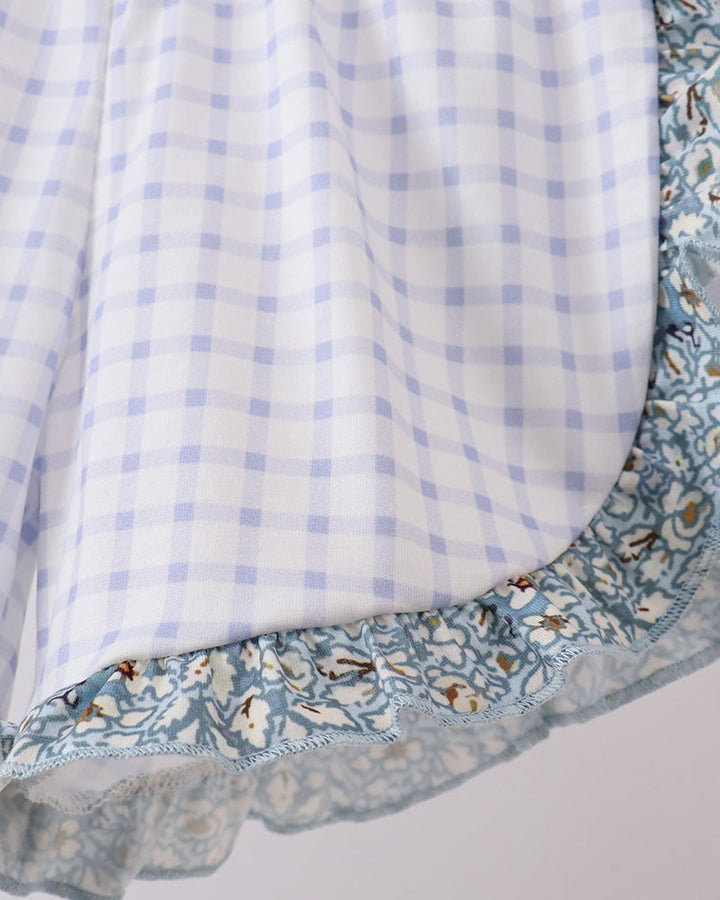 Close-up of a fabric with blue checkered pattern and floral border on a white background