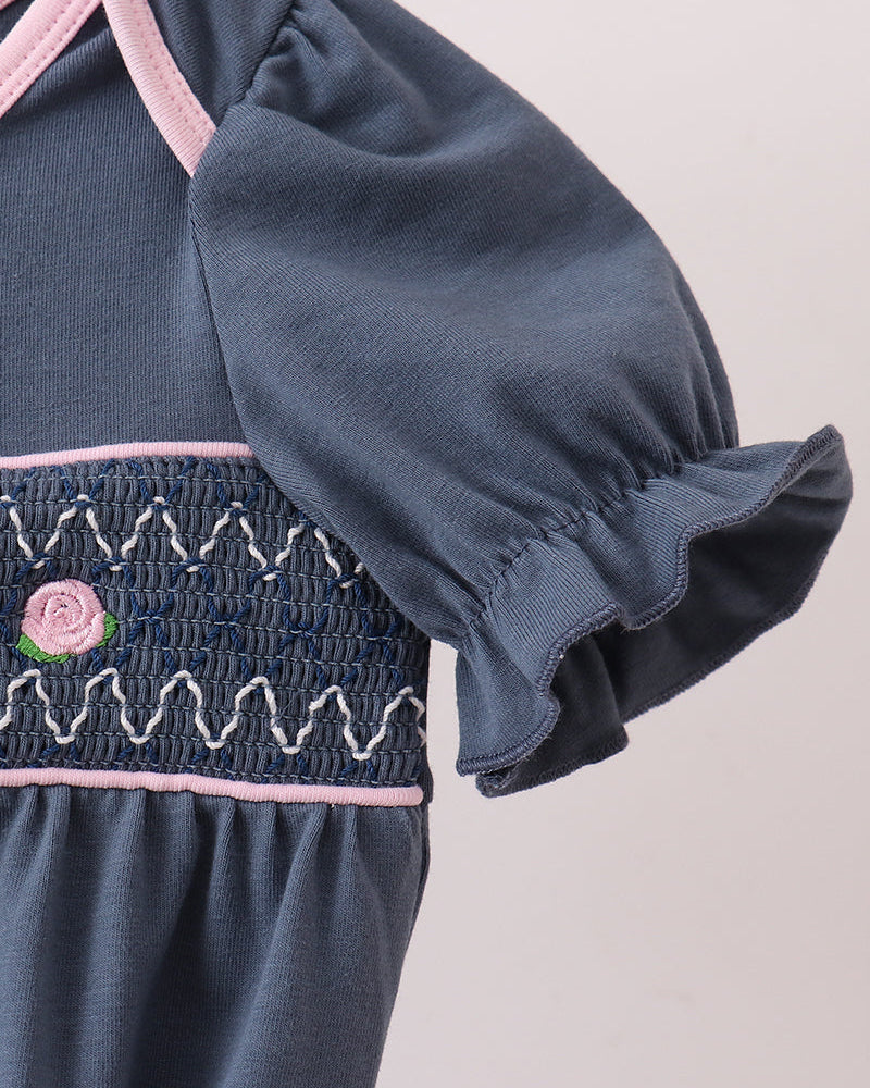 Dark blue smocked bodice with embroidered rose, pink trim, and gathered ruffle sleeves