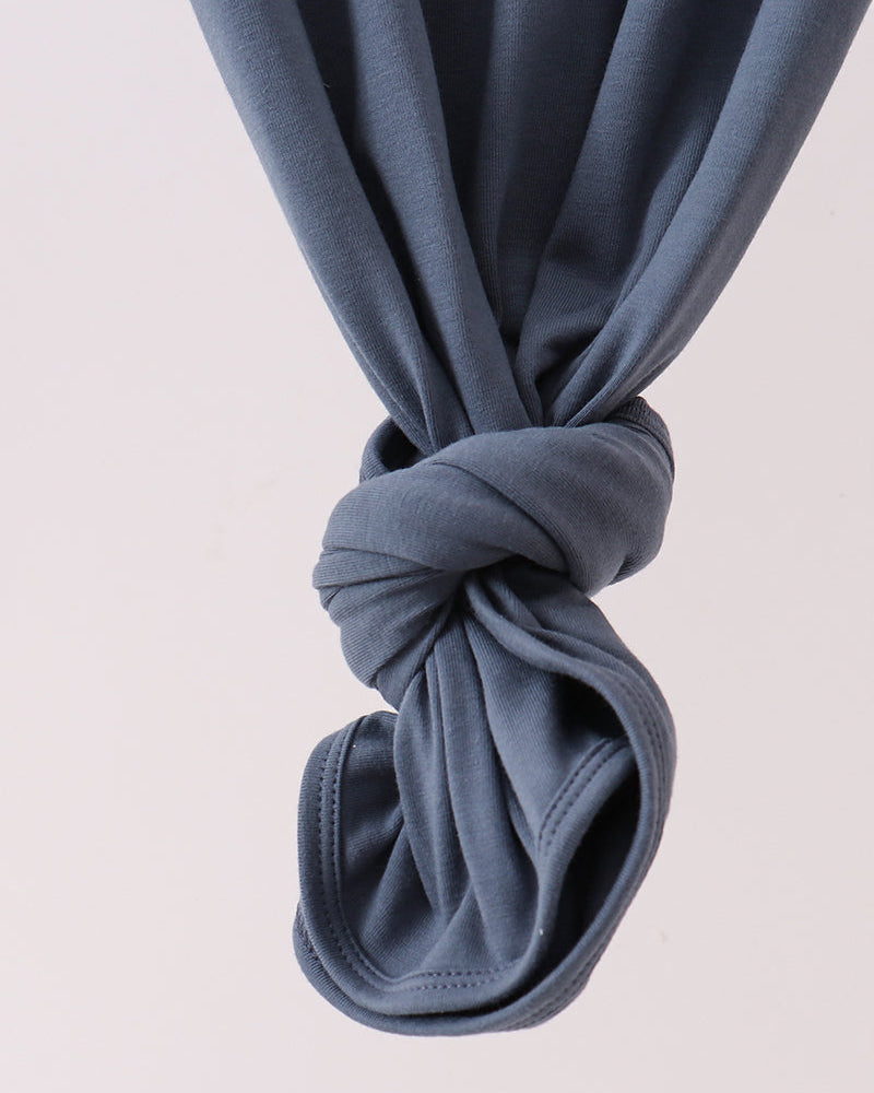 Dark blue knotted fabric detail at hem of smocked baby gown
