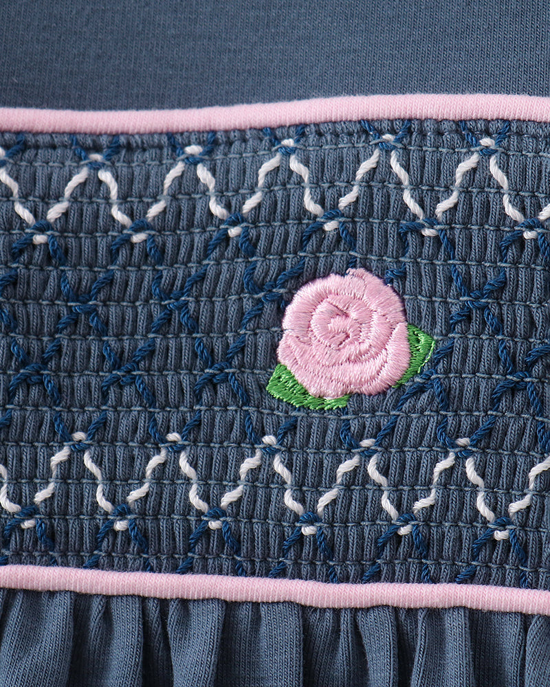 Smocked dark blue romper panel with pink rose embroidery and pink trim stripe