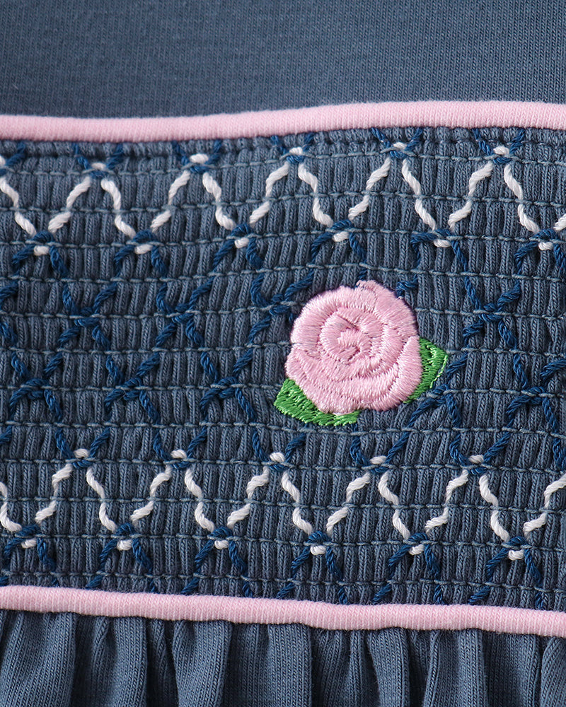 Dark blue smocked bodice with pink trim and small pink flower applique
